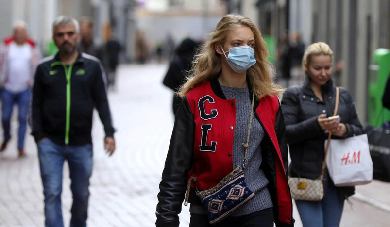 People with and without protective masks walk on the street in Amsterdam